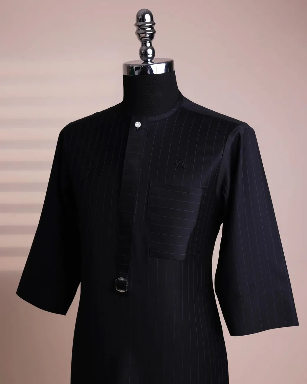 A black pencil stripe, mug-shaped pocket, front flap with buckle strap and silver Swarovski button, 3/4 sleeve African senator kaftan.