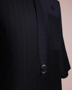A black pencil stripe, mug-shaped pocket, front flap with buckle strap and silver Swarovski button, 3/4 sleeve African senator kaftan.