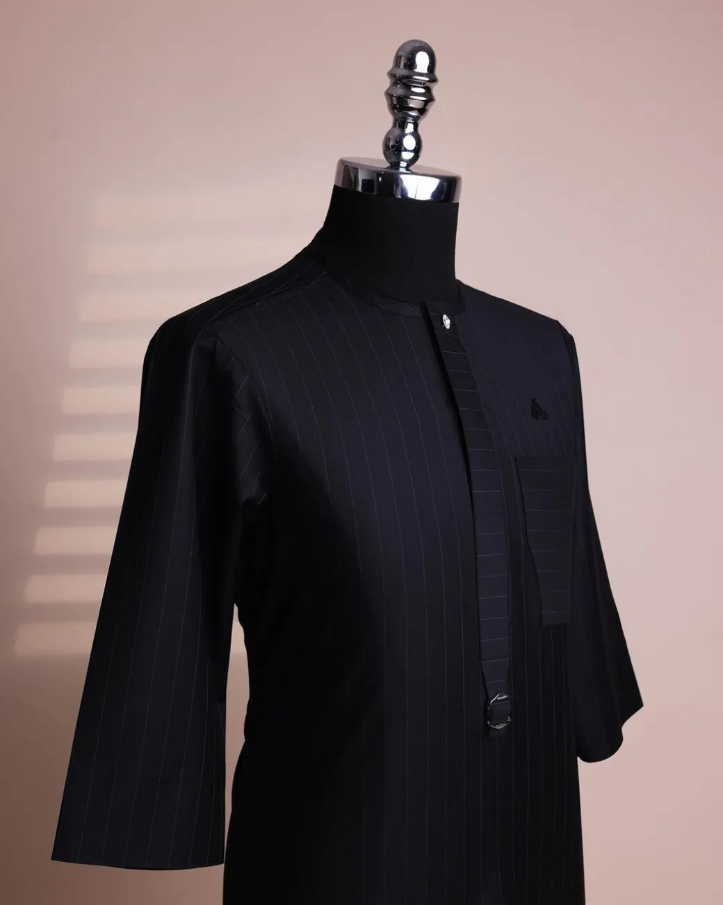 A black pencil stripe, mug-shaped pocket, front flap with buckle strap and silver Swarovski button, 3/4 sleeve African senator kaftan.