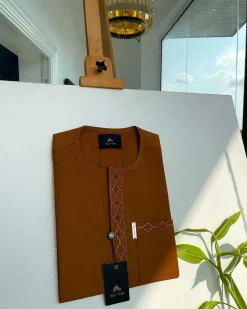 A caramel brown flap and pocket undulating with connected lane embroidery detailing African traditional senator Kaftan native