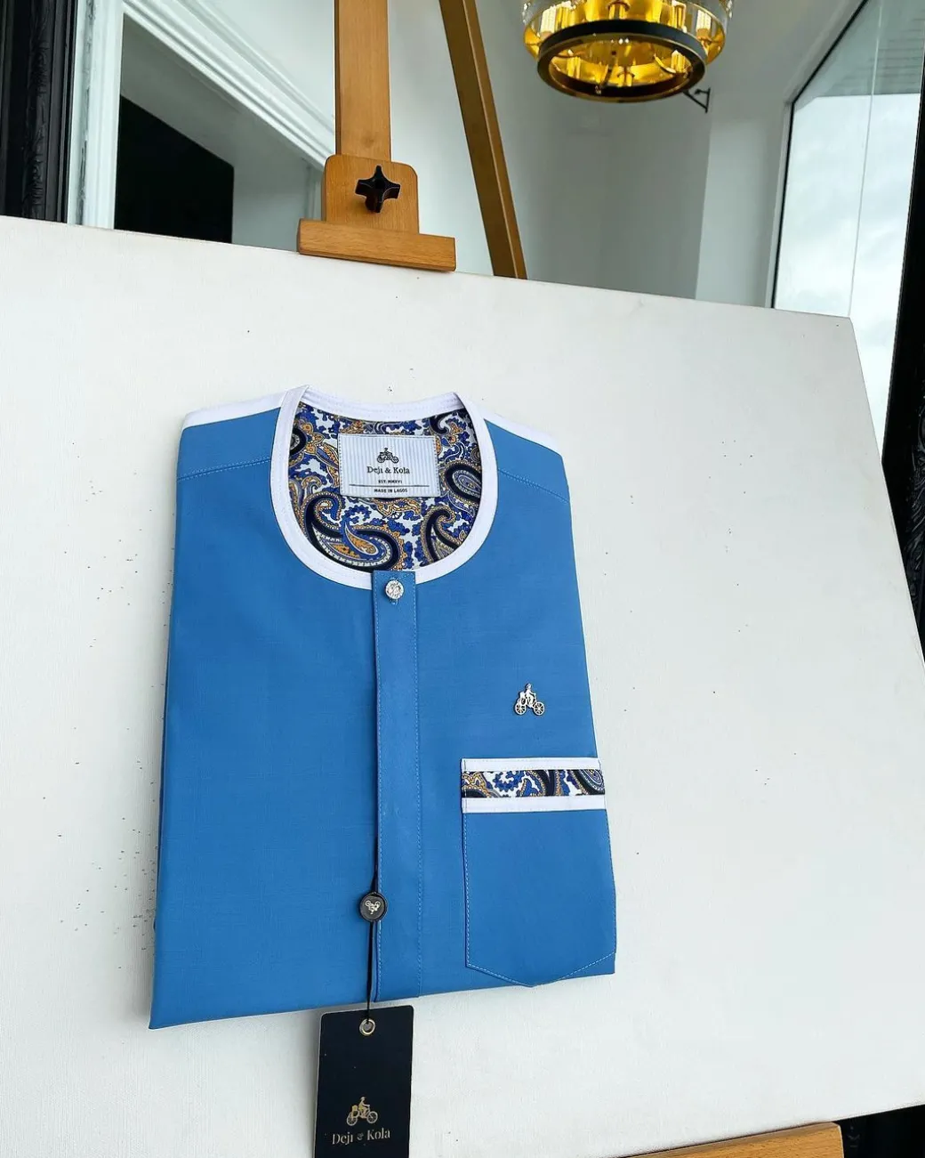 A cerulean blue, vertical flap with horizontal paisley patch pocket detailing and a Swarovski button African traditional senator kaftan native
