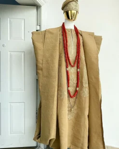 A champagne gold aso oke regal agbada, dashiki, sokoto, red and gold mix coral bead, matching hand woven Yoruba hat, and a long gold chain with a Jesus piece.