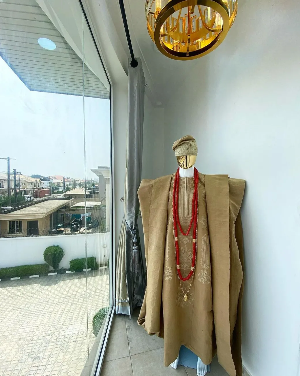 A champagne gold aso oke regal agbada, dashiki, sokoto, red and gold mix coral bead, matching hand woven Yoruba hat, and a long gold chain with a Jesus piece.