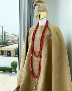 A champagne gold aso oke regal agbada, dashiki, sokoto, red and gold mix coral bead, matching hand woven Yoruba hat, and a long gold chain with a Jesus piece.