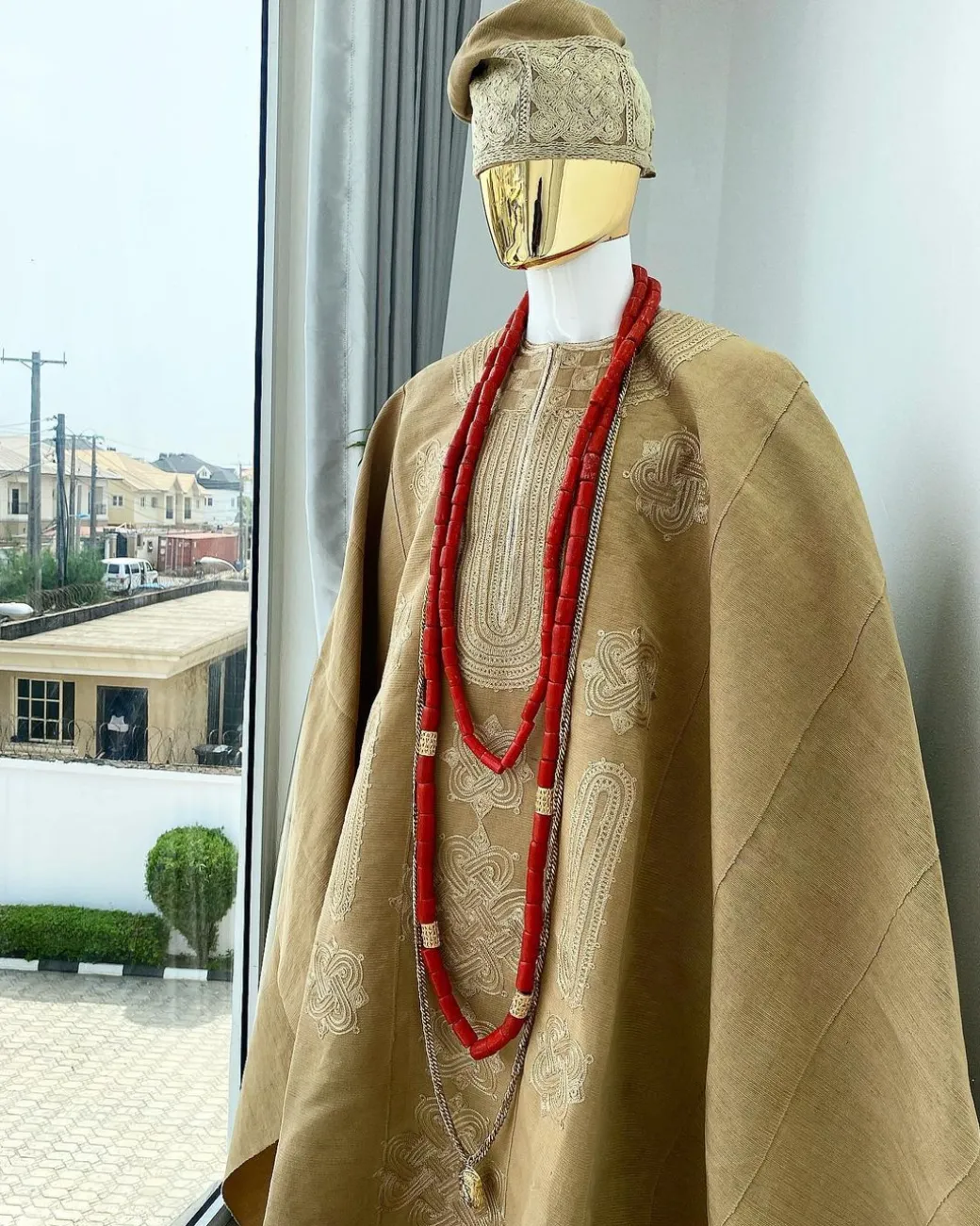 A champagne gold aso oke regal agbada, dashiki, sokoto, red and gold mix coral bead, matching hand woven Yoruba hat, and a long gold chain with a Jesus piece.