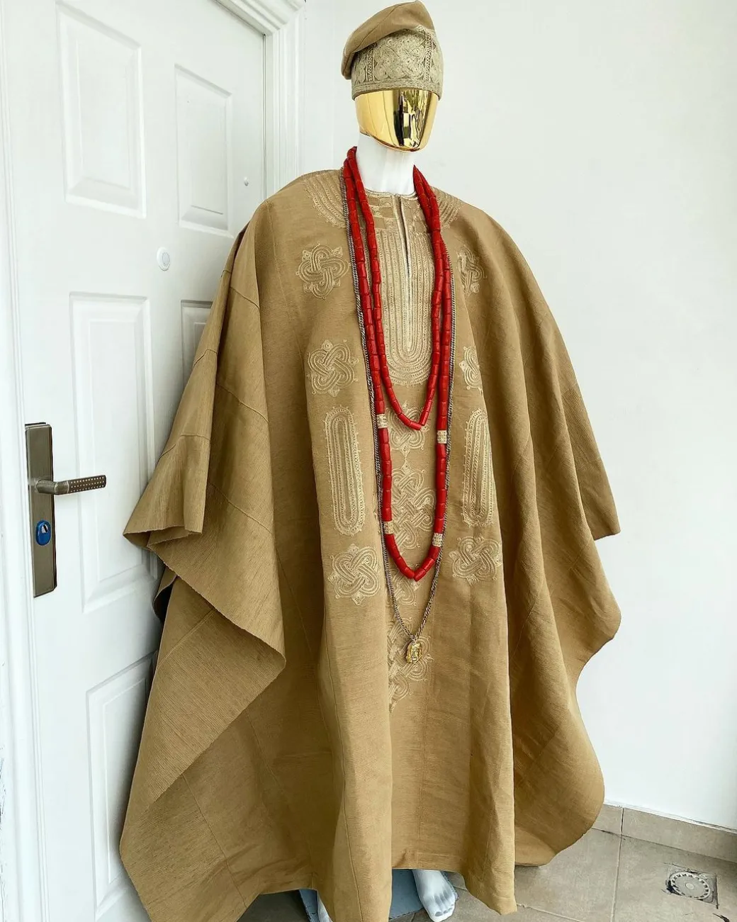 A champagne gold aso oke regal agbada, dashiki, sokoto, red and gold mix coral bead, matching hand woven Yoruba hat, and a long gold chain with a Jesus piece.