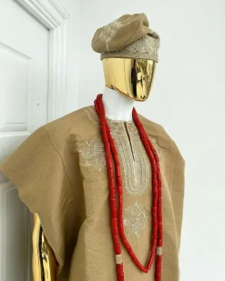 A champagne gold aso oke dashiki, with a floral and ancient style shaped embroidery design, hand woven Yoruba hat, an extra length red and gold coral bead.