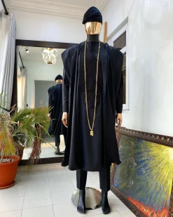 A charcoal black agbada, Jesus piece long fashion chain and hand woven aso oke Yoruba hat.