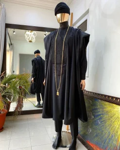 A charcoal black agbada, Jesus piece long fashion chain and hand woven aso oke Yoruba hat.