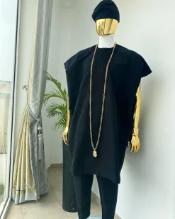 A charcoal black aso dashiki with a floral and box-shaped embroidery design, a hand-weaved Yoruba hat, and a gold Jesus timepiece
