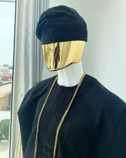 A charcoal black aso dashiki with a floral and box-shaped embroidery design, a hand-weaved Yoruba hat, and a gold Jesus timepiece