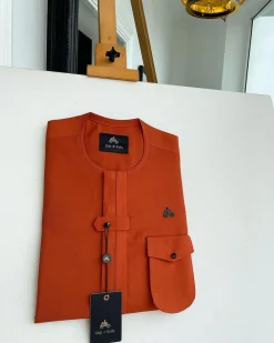 A fire orange, double vertical flap with horizontal closed detailing, combat pocket, and Swarovski button details African traditional senator kaftan native
