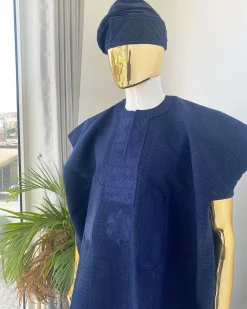 A navy blue aso oke dashiki with a floral and box-shaped embroidery design and hand-embroidered Yoruba hat