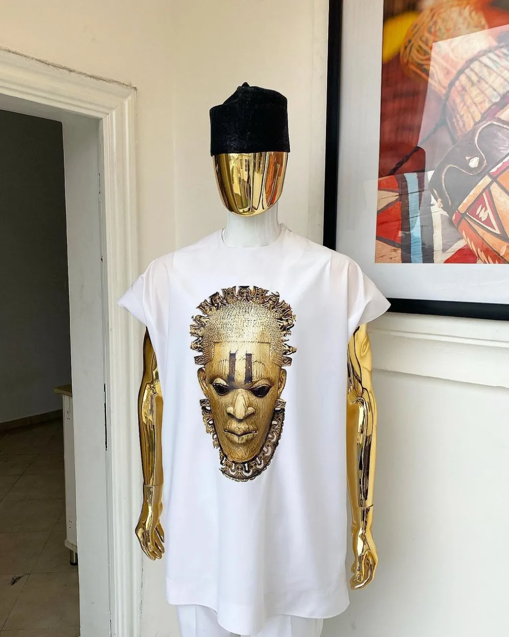 A white “daftan” with the Benin royalty prints and black Fulani hat