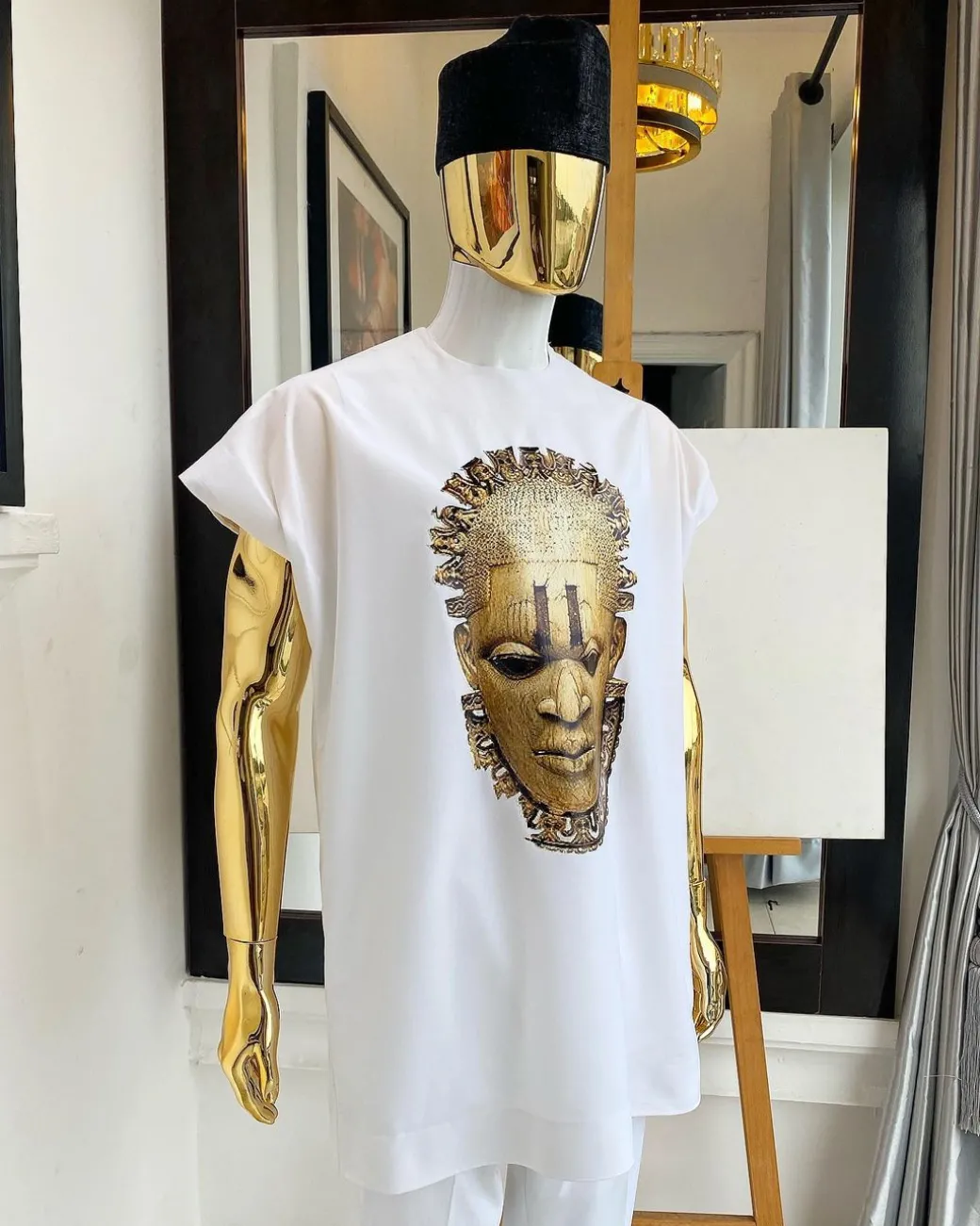 A white “daftan” with the Benin royalty prints and black Fulani hat